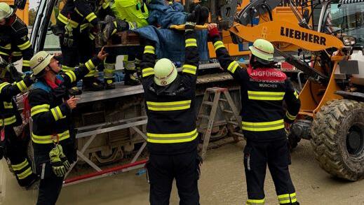Feuerwehrleute kümmern sich um den Patienten und heben ihn aus dem 70-Tonnen-Kran.