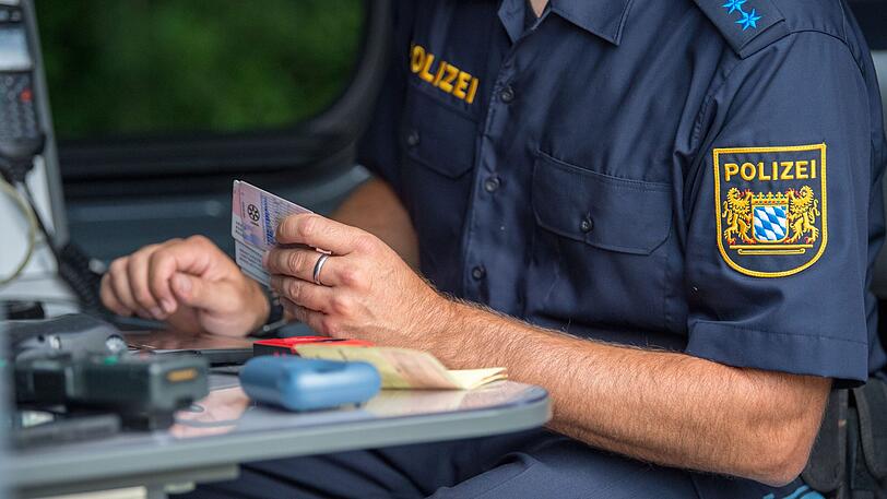 Ein Beamter der bayerischen Grenzpolizei kontrolliert am Grenzübergang Kirchdorf Dokumente von Autofahrern.
