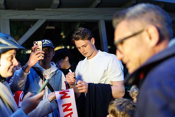 Torhüter Jonas Urbig schreibt Autogramme, bevor er mit seinen Teamkollegen feiert. Torhüter Jonas Urbig schreibt Autogramme, bevor er mit seinen Teamkollegen feiert.