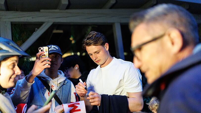 Torhüter Jonas Urbig schreibt Autogramme, bevor er mit seinen Teamkollegen feiert. Torhüter Jonas Urbig schreibt Autogramme, bevor er mit seinen Teamkollegen feiert.
