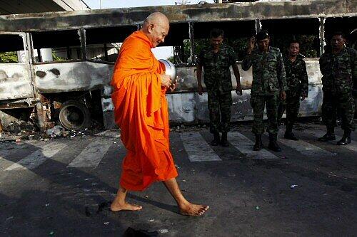 Mönch vor ausgebranntem Bus in Bangkok