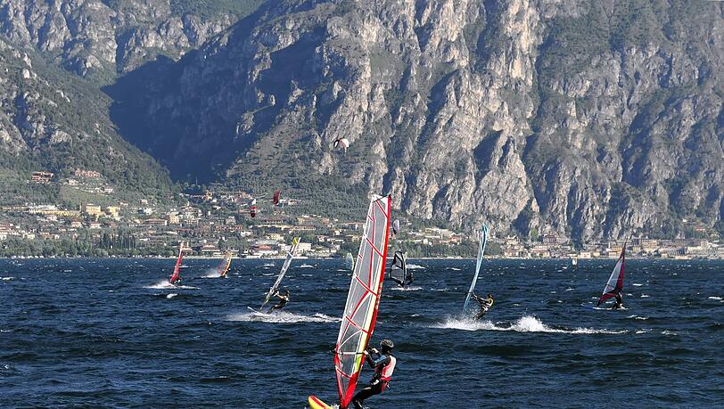 Windsurfer surfen bei starkem Wind auf dem Gardasee bei Malcesine. Windsurfer surfen bei starkem Wind auf dem Gardasee bei Malcesine.