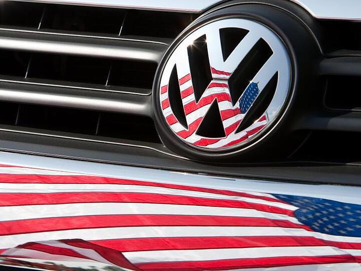 Die US-Fahne spiegelt sich in Logo und Kühlergrill eines VW.