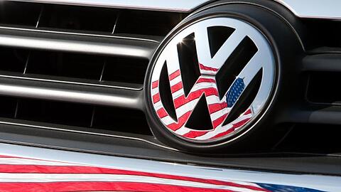 Die US-Fahne spiegelt sich in Logo und Kühlergrill eines VW.
