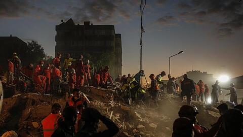 Rettungskr&auml;fte suchen in den Tr&uuml;mmern eines eingest&uuml;rzten Geb&auml;udes in Izmir nach &Uuml;berlebenden.