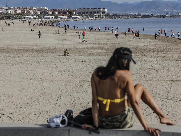 Eine Frau genießt ein Sonnenbad am Strand von Malvarrosa in Valenica.