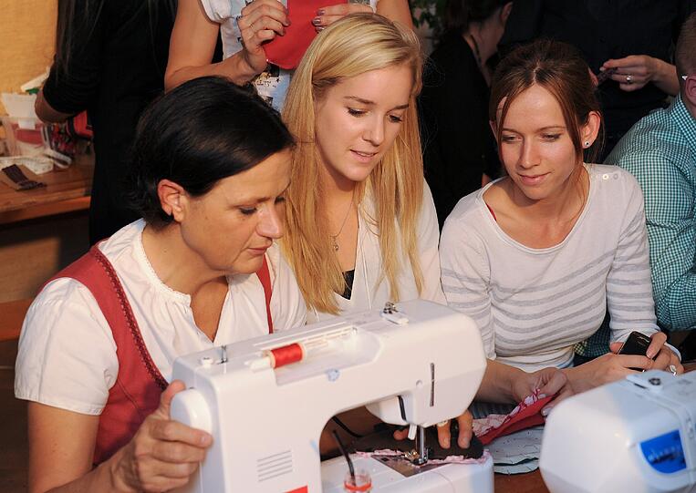 Burda-Mitarbeiterin Rosemarie (links) mit zwei Teilnehmerinnen an der Nähmaschine.