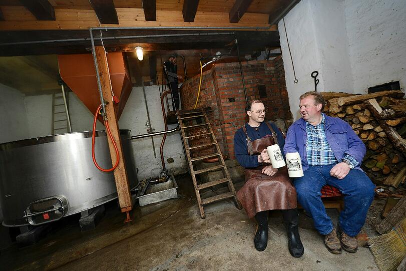 Thomas Bretscher (l) und Egon Klöffel stoßen in der Gemeindebrauerei in Thundorf mit ihrem selbstgebrauten Bier an.