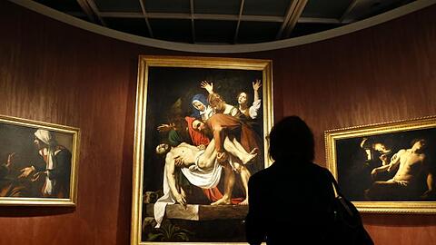 Besucher betrachten das Bild "Die Grablegung Christi" von Michelangelo Merisi, bekannt als Caravaggio. Foto: Yuri Kochetkov/Archiv
