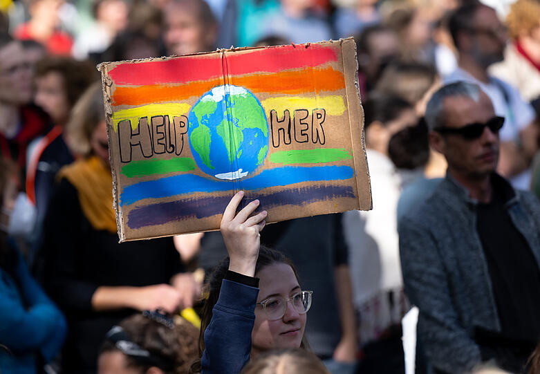 Eine Frau nimmt an einer Demonstration zum globalen Klimastreik teil und hält ein Plakat mit der Aufschrift „Help Her“ in den Händen. Sie folgen dem Aufruf der Bewegung "Fridays for Future". Die Teilnehmer fordern unter anderem eine Abkehr von fossilen Brennstoffen.