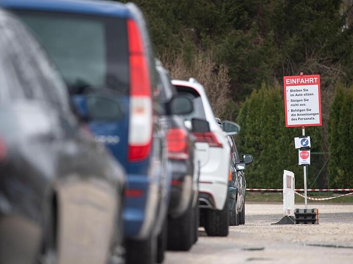 Autos warten an einer "Drive-In"-Teststation für den Coronavirus vor der Einfahrt. Foto: Marijan Murat/dpa