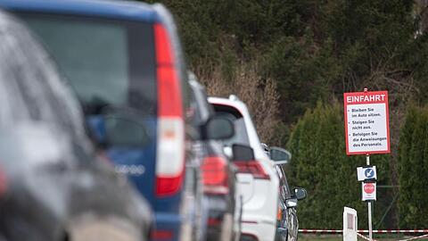 Autos warten an einer "Drive-In"-Teststation für den Coronavirus vor der Einfahrt. Foto: Marijan Murat/dpa