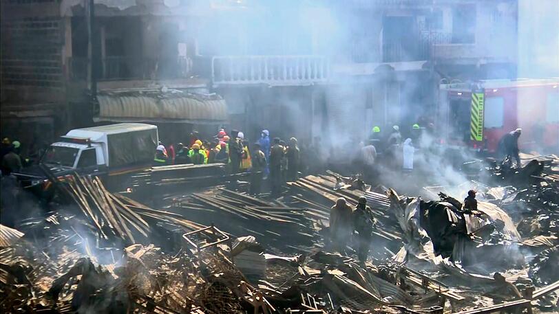 Kenia, Nairobi: Rettungskräfte beraten sich nach einem Brand auf einem Markt in der kenianischen Hauptstadt Nairobi, bei dem mindestens 15 Menschen ums Leben gekommen sind.