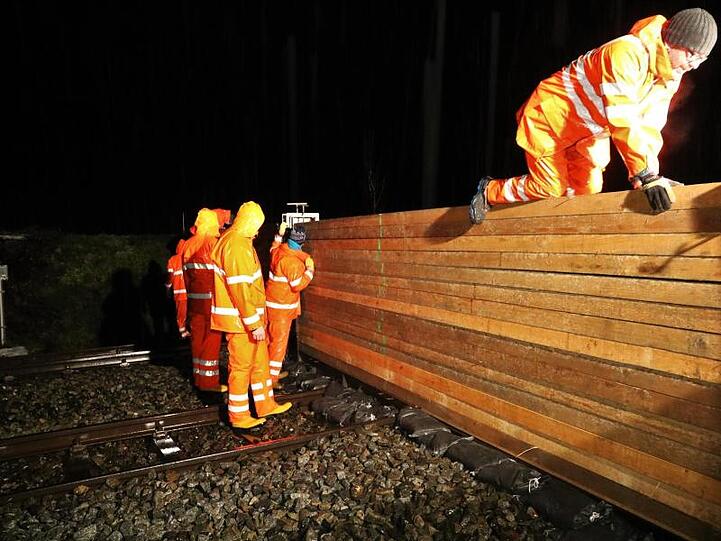 Mitarbeiter der Stadt Immenstadt bauen einen Schutzwall über eine Bahnstrecke. Auch für die Iller gibt es eine Hochwasserwarnung.