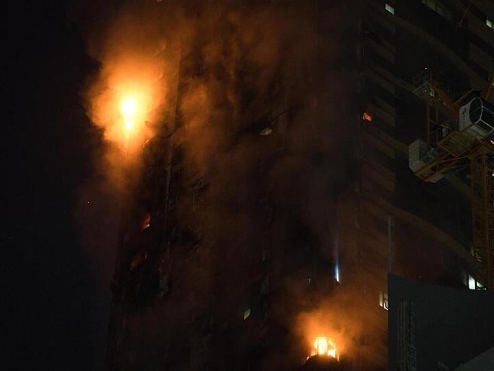 Ein Feuer brennt an der Seite des Hochhauses in Schardscha.