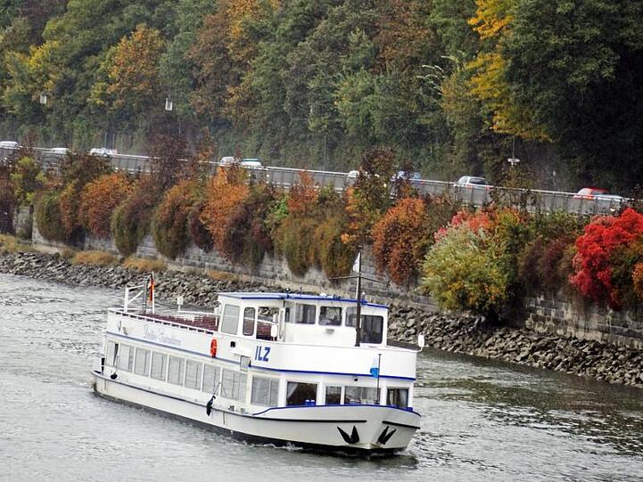 Ein Ausflugsschiff fährt auf der Donau bei Passau (Niederbayern) vor herbstlich gefärbten Bäumen. Foto: Armin Weigel dpa/Archiv