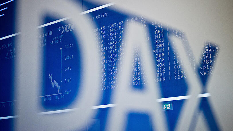 Im Schriftzug "DAX" spiegelt sich die große Anzeigetafel mit dem bis dahin erreichten Kursverlauf im Handelssaal der Börse in Frankfurt am Main.