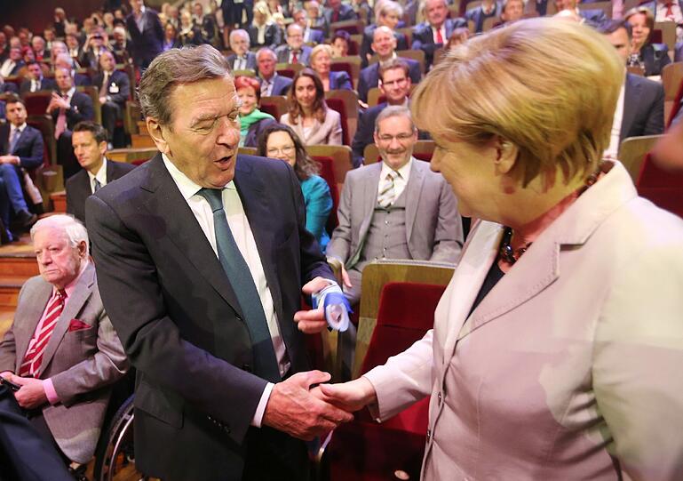 Schwarze Kanzlerin mit roten Altkanzlern: Angela Merkel schüttelt Gerhard Schröder die gesunde Hand, Helmut Schmidt (ganz links) bleibt sehr gelassen.