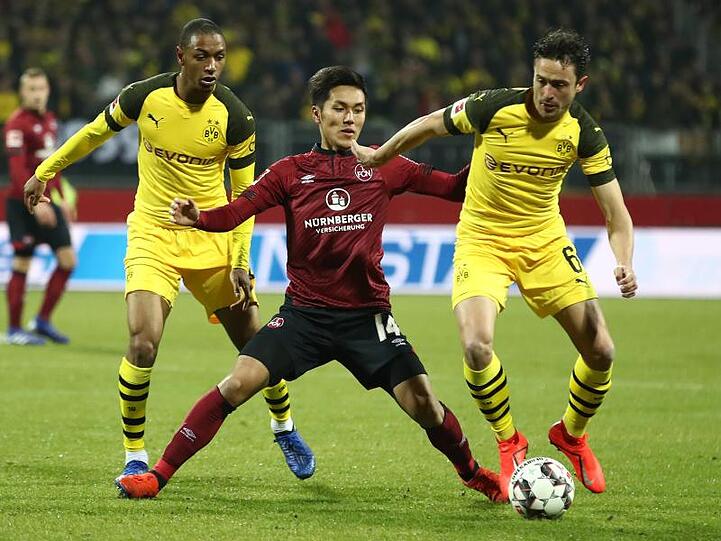 Der Nürnberger Yuya Kubo (M) kämpft mit den Dortmundern Abdou Diallo (l) und Thomas Delaney um den Ball. Foto: Daniel Karmann