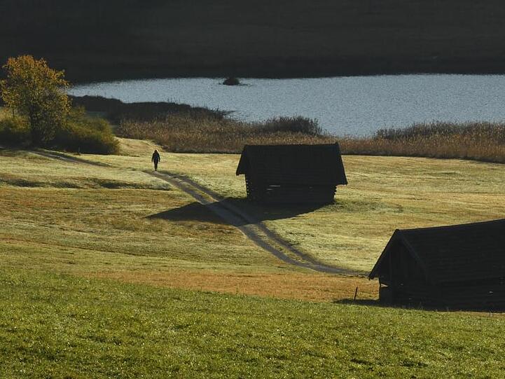 Eine Frau geht am Morgen am Geroldsee spazieren. Foto: Angelika Warmuth/dpa