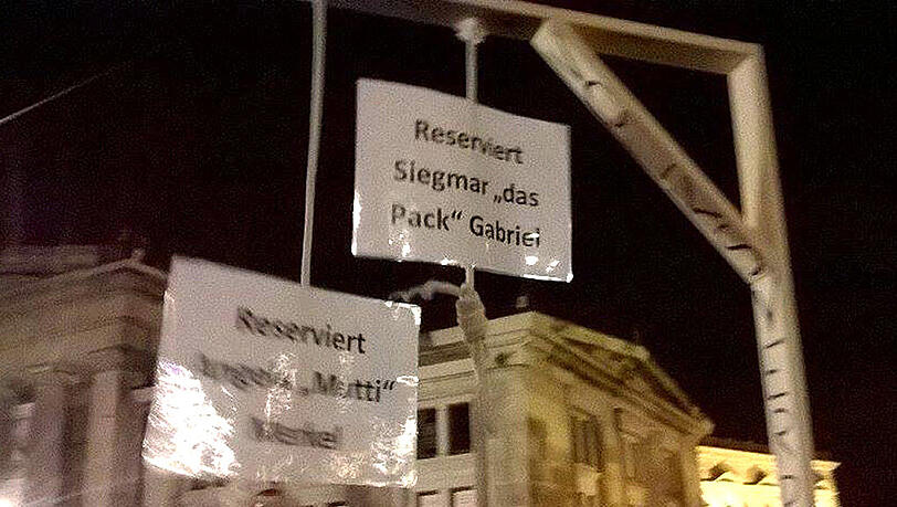 Teilnehmer der Pegida Demonstration halten am 12.10.2015 in Dresden einen gebastelten Galgen hoch, an dem Schilder mit der Aufschrift "Reserviert Angela 'Mutti' Merkel" und "Reserviert Siegmar 'Das Pack' Gabriel" zu sehen sind. Teilnehmer der Pegida Demonstration halten am 12.10.2015 in Dresden einen gebastelten Galgen hoch, an dem Schilder mit der Aufschrift "Reserviert Angela 'Mutti' Merkel" und "Reserviert Siegmar 'Das Pack' Gabriel" zu sehen sind.