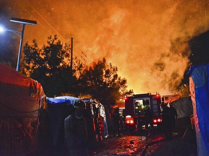 Feuerwehrleute kämpfen gegen den Brand in dem überfüllten Migrantenlager.