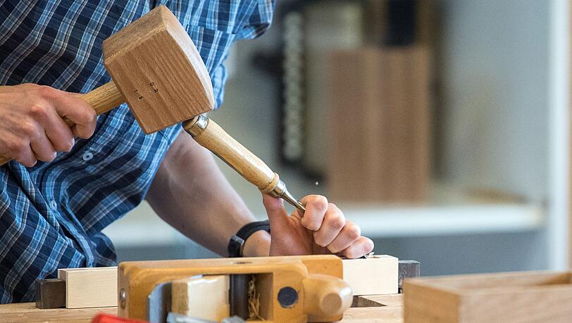 Ein Auszubildender arbeitet mit Hammer und Stechmeisel an einem Werkstück.