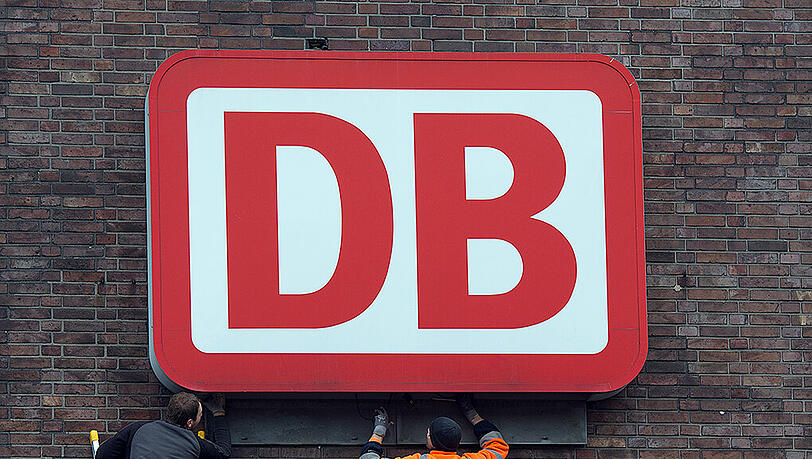 Monteure arbeiten an einem Unternehmensschild der Deutschen Bahn. Foto: Federico Gambarini/Illustration Monteure arbeiten an einem Unternehmensschild der Deutschen Bahn. Foto: Federico Gambarini/Illustration