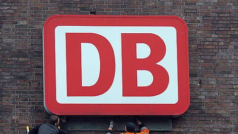 Monteure arbeiten an einem Unternehmensschild der Deutschen Bahn. Foto: Federico Gambarini/Illustration