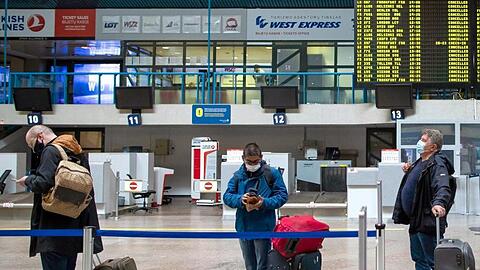 Passagiere mit Smartphones in einer Schlange im Internationalen Flughafen von Vilnius.