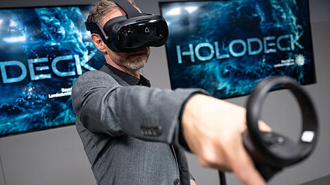 Ralf Breker, Leiter der forensischen Medientechnik beim LKA Bayern, steht mit einer VR-Brille im Tatort-Virtual-Reality-Raum.