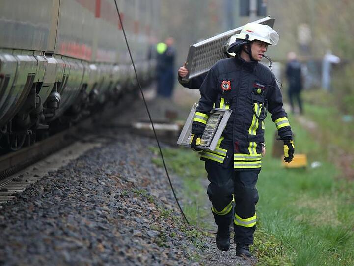 Umsteigen bitte: Feuerwehrleute tragen Brückenteile, um den ICE mit dem Ersatzzug zu verbinden.