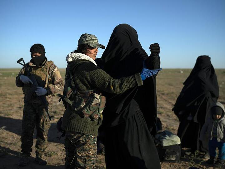 Eine Frau wird von einer Soldatin in einem Kontrollbereich der SDF durchsucht, nachdem sie aus dem verbliebenen Gebiet des IS evakuiert wurde.