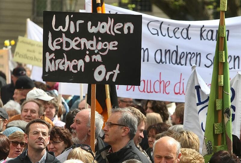 Katholiken stehen am Samstag (21.04.2012) mit Transparenten auf dem Domplatz von Augsburg (Schwaben). Im Rahmen einer Kundgebung demonstrieren sie gegen die geplante Pastoralreform des Bistums Augsburg.