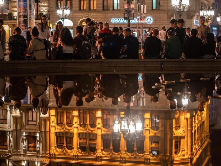 Menschen sitzen am Brunnen vor der Alten Oper in Frankfurt. Dort wurde in der Nacht nur friedlich gefeiert.