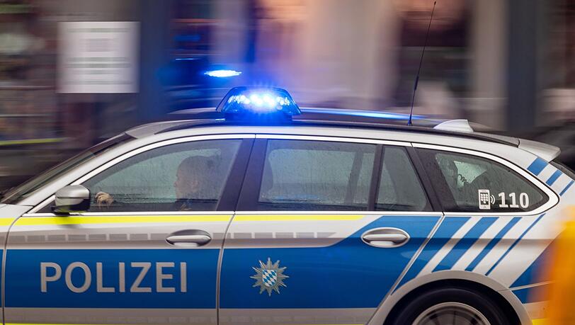 Ein Fahrzeug der bayerischen Polizei fährt mit Blaulicht durch die Innenstadt.