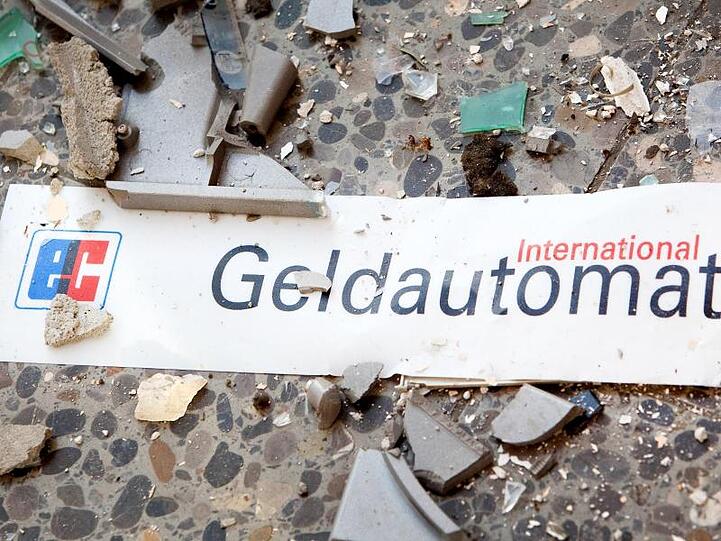 Splitter und ein Schild mit der Aufschrift "Geldautomat" liegen auf dem Fußboden vor einem gesprengten Geldautomaten (Archiv).
