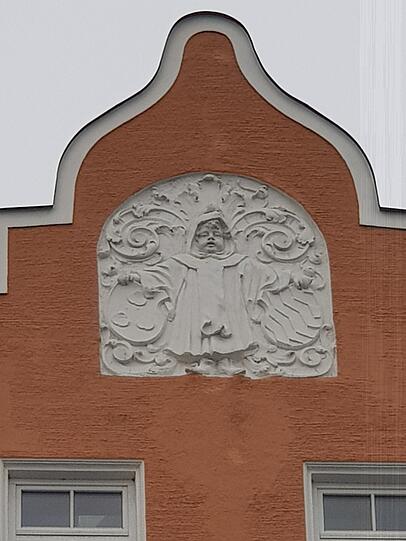 Unten Verkehrsgetöse, oben Kindl: ein Giebel am Rosenheimer Platz.