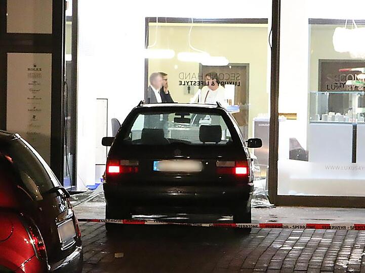 Ein Auto steht in der Scheibe eines Juwelier-Geschäftes.