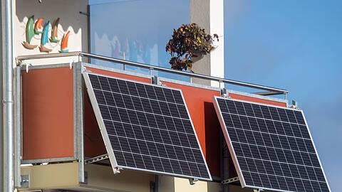 Solarmodule für ein sogenanntes Balkonkraftwerk hängen an einem Balkon.