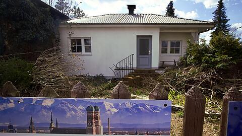 Ein zum Abriss bestimmtes Münchner Einfamilienhaus und das Werbeplakat einer Immobiliengesellschaft.