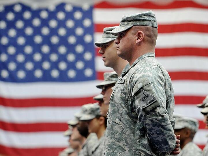 US-Soldaten stehen nach ihrer Ankunft auf der US-Airbase vor einer US-Flagge. Foto: Frank May/dpa/Archivbild