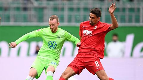 Wolfsburgs Maximilian Arnold (l) kämpft mit Augsburgs Rani Khedira um den Ball.