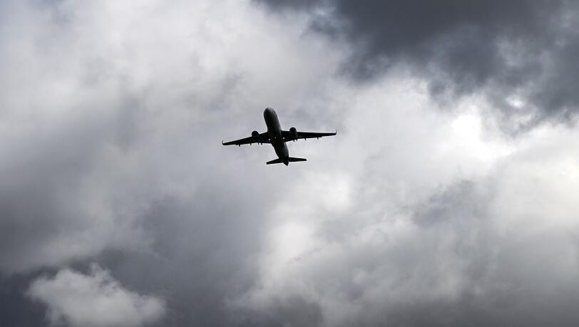 Über einem Flugzeug türmen sich dunkle Wolken.