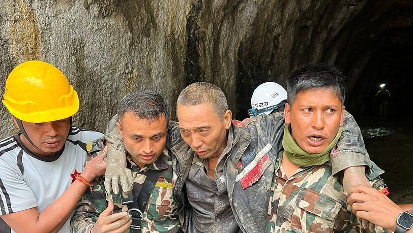 Rettungskr&auml;fte tragen einen &Uuml;berlebenden der Sturzflutkatastrophe in Nepal.