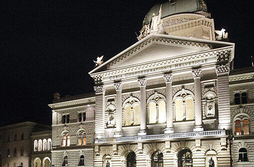 Und zwar mit der Bundesstadt der Schweiz: Bern. Auf dem Bild sehen Sie das beleuchtete Bundeshaus in Bern bei Nacht.