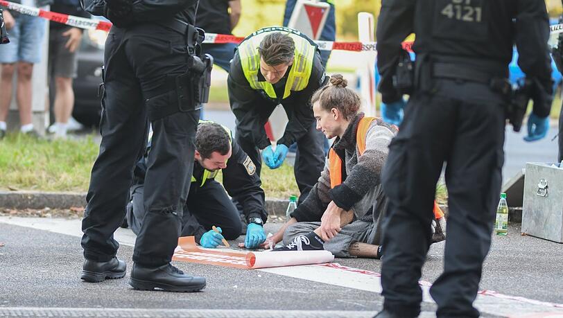 Polizisten lösen die Hand eines Klimaaktivisten von der Straße. Polizisten lösen die Hand eines Klimaaktivisten von der Straße.
