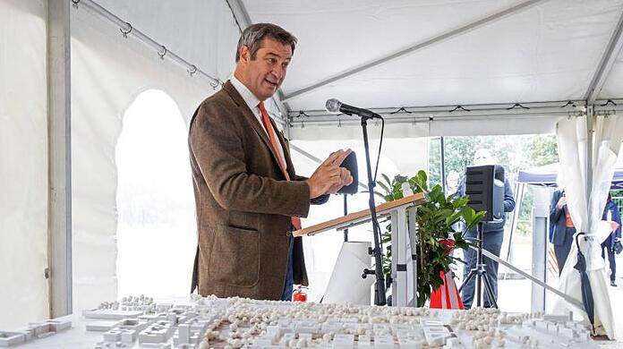 Markus Söder spricht während dem symbolischen Spatenstich für den Bau der neuen TU Nürnberg neben einem Architekturmodell.