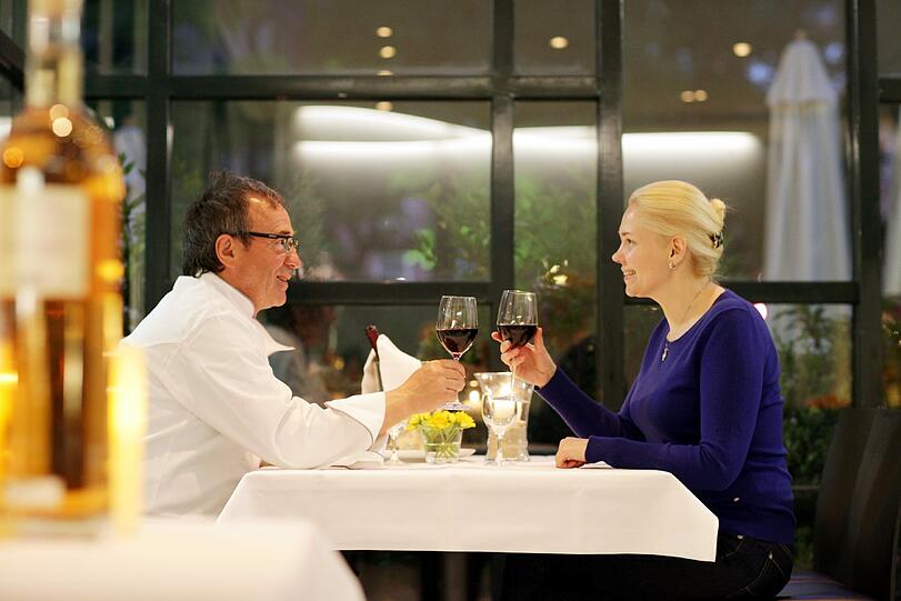 Werner Hunsinger stößt mit einer Besucherin an: Im Restaurant serviert er alles, von der Fischsuppe bis zum Vier-Gänge-Menü.