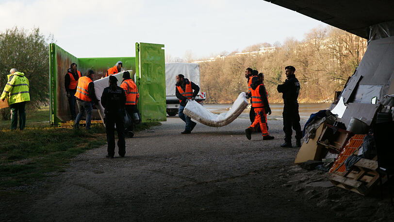 Mitarbeiter der Stadtreinigung werfen eine Matratze in den Container.